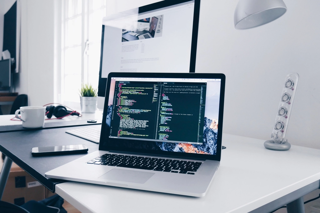 コードが表示されたノートパソコンとデスク